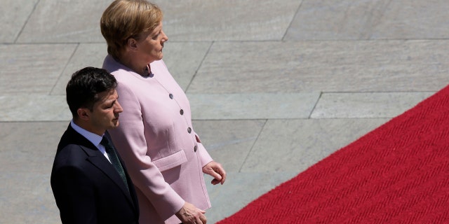 German Chancellor Angela Merkel, right, and Ukrainian President Volodymyr Zelenskiy, left, listen to the national anthems during the welcoming ceremony, prior to a meeting at the chancellery in Berlin, Germany, Tuesday, June 18, 2019.