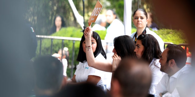 A woman bids during an auction of seized properties from drug traffickers and others, in Mexico City, Mexico June 23, 2019.