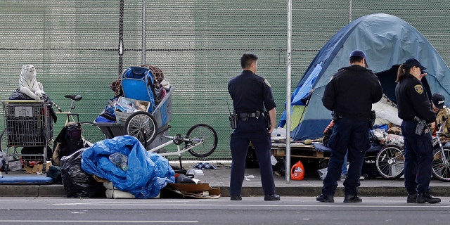 San Francisco police officers wait while homeless people collect their belongings in San Francisco.