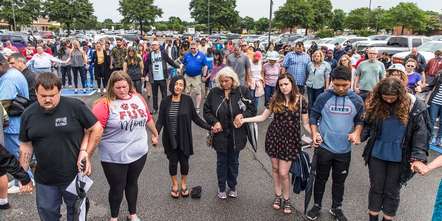 The community prayed together on Saturday during the vigil at Strawbridge Marketplace for the victims of the shooting. (Daniel Sangjib Min/Richmond Times-Dispatch via AP)