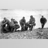 Soldiers carry troop onto beach during D-Day