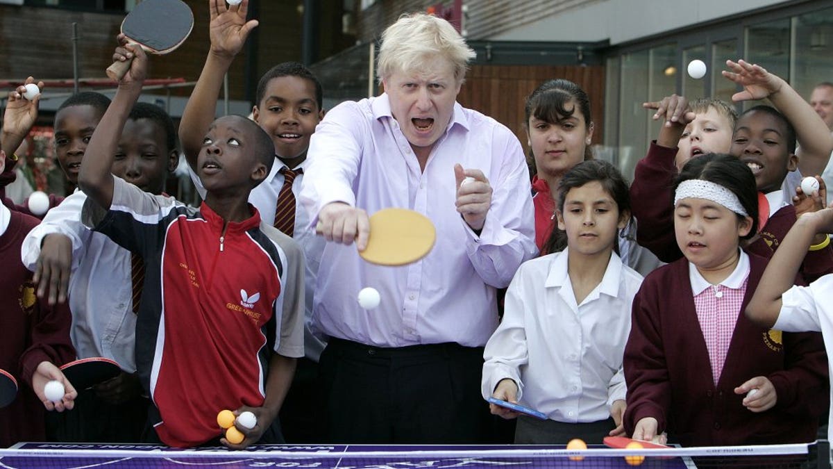 In this Friday, June 25, 2010 file photo, Mayor of London Boris Johnson, center, poses for photographers as he plays a game of table tennis with pupils in London.