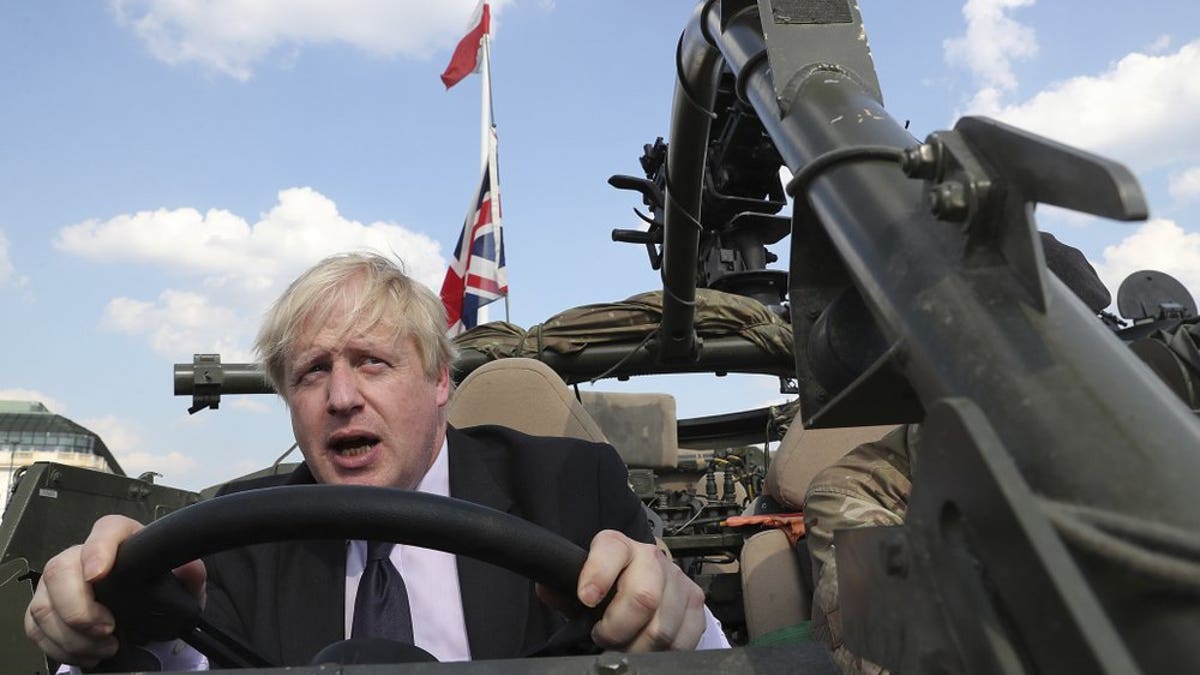 In this Thursday, June 21, 2018 file photo Britain's Foreign Secretary Boris Johnson talks to a British armed forces serviceman based in Orzysz, in northeastern Poland, during a ceremony at the Tomb of the Unknown Soldier and following talks on security with his Polish counterpart Jacek Czaputowicz in Warsaw, Poland. Boris Johnson aspires to be a modern-day Winston Churchill. Critics fear he's a British Donald Trump.?