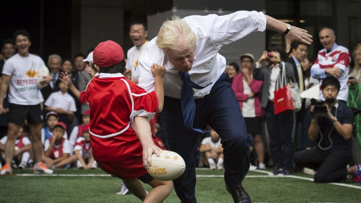 In this Oct. 15, 2015 file photo, Boris Johnson takes part in a Street Rugby tournament in a Tokyo street, wiping out a Japanese school boy in the process
