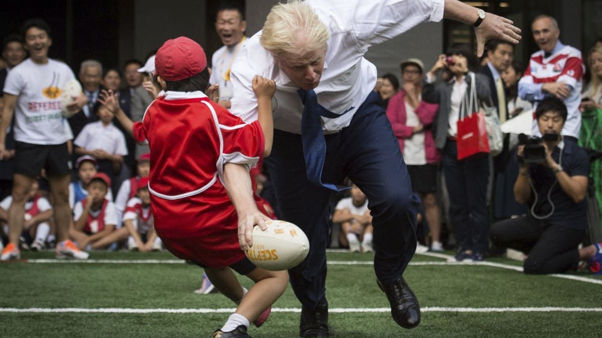 In this Oct. 15, 2015 file photo, Boris Johnson takes part in a Street Rugby tournament in a Tokyo street, wiping out a Japanese school boy in the process