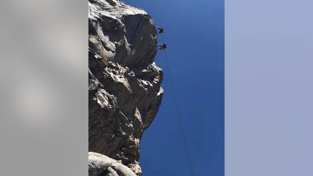 Paul and his son, Riley, rappel down the mountain.