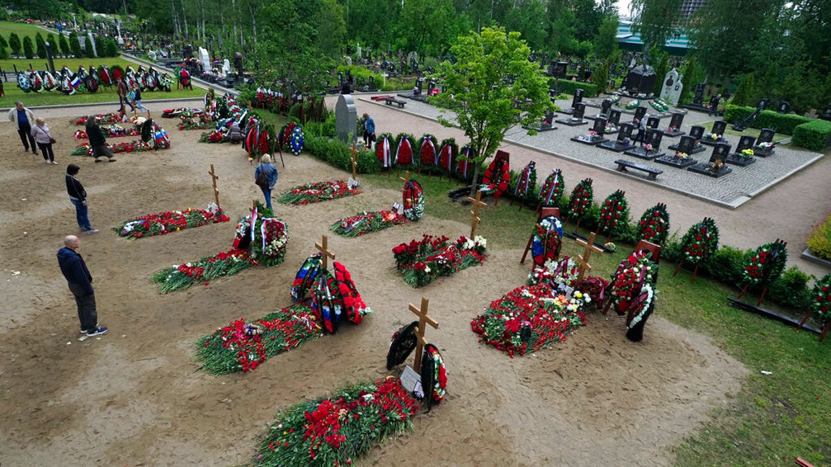 People lay flowers at the graves of the 14 crew members who died in a fire on a Russian navy's deep-sea research submersible, next to the graves of crew members of Kursk submarine, right, at the Serafimovskoye memorial cemetery during a funeral ceremony in St. Petersburg, Russia, Saturday, July 6, 2019.