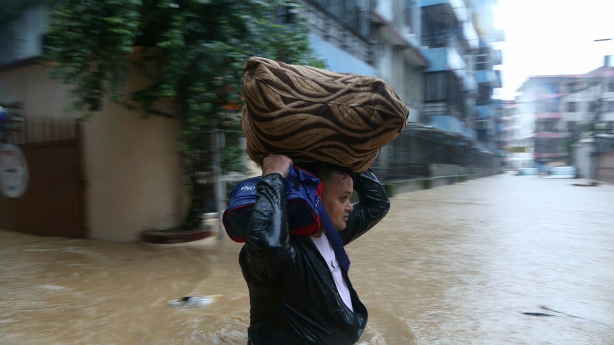 A Nepalese man wades with his belonging through a flooded street in Kathmandu, Nepal on Friday. (AP Photo/Niranjan Shrestha)