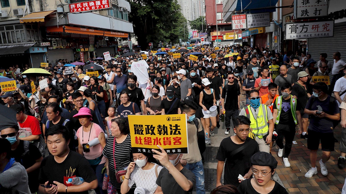 Protesters hold up words that read: "Strict enforcing of law against smugglers of grey goods" in Hong Kong Saturday, July 13, 2019. Several thousand people are marching in Hong Kong against traders from mainland China in what is fast becoming a summer of unrest in the semi-autonomous Chinese territory. (AP Photo/Kin Cheung)