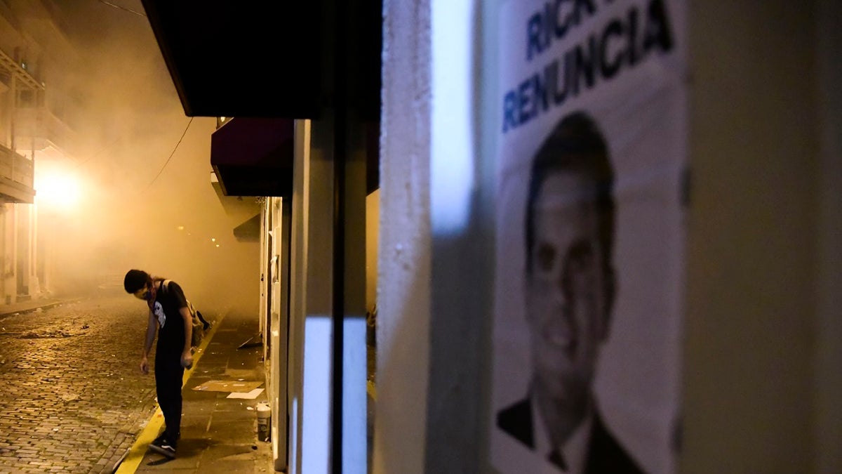 A protester stands near a poster calling for the resignation of Gov. Ricardo Rossello, in San Juan, Puerto Rico, Monday. (AP Photo/Carlos Giusti)
