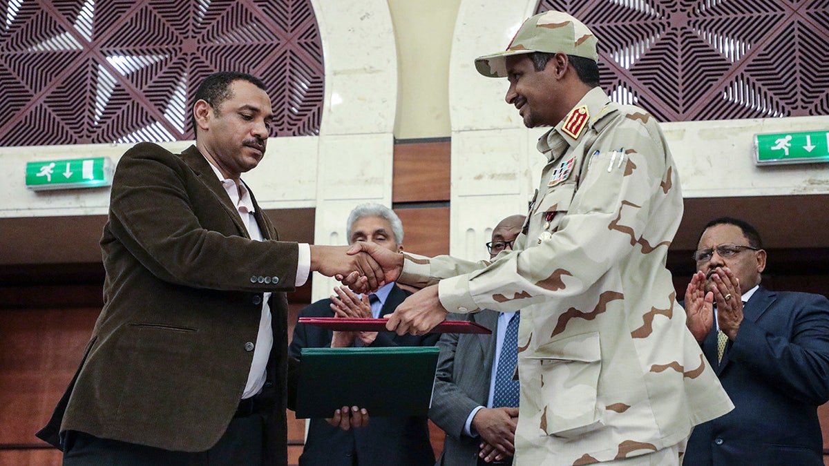 Gen. Mohammed Hamdan Dagalo, right, and Sudan's pro-democracy movement leader Ahmad al-Rabiah shake hands after signing a power-sharing document in Khartoum, Sudan, Wednesday, July 17, 2019. 