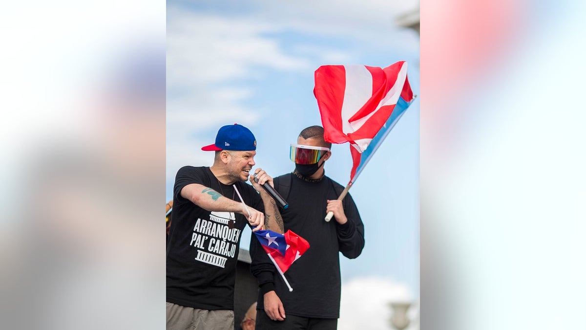 Puerto Rican rapper Rene Juan Perez known by his stage name of Residente, left, speaks to the crowd in front of the Puerto Rican Capitol in San Juan Wednesday (AP Photo/Dennis M. Rivera Pichardo)