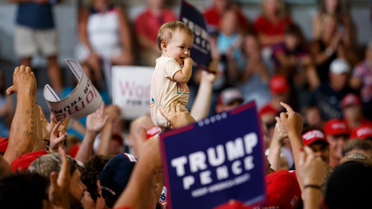 A baby is held high in the audience as President Donald Trump speaks at a campaign rally at Williams Arena in Greenville, N.C., Wednesday, July 17, 2019. (AP Photo/Carolyn Kaster)