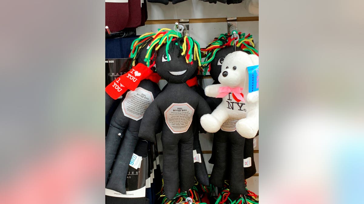 This undated photo provided by New Jersey state Assemblywoman Angela McKnight shows three "Feel Better Dolls" sharing the shelf with a stuffed animal bearing an "I Love New York" message at a One Dollar Zone store in Bayonne, N.J. The black rag "Feel Better" dolls that came with instructions to "find a wall" and slam the toy against it have been pulled from three stores after customers and the lawmaker said they were offensive. (Angela McKnight via AP)