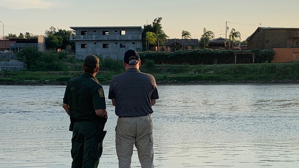 A U.S. Border Patrol official and the U.S. Drug Czar Jim Carroll look across the Rio Grande--the river that separates the U.S. and Mexico.