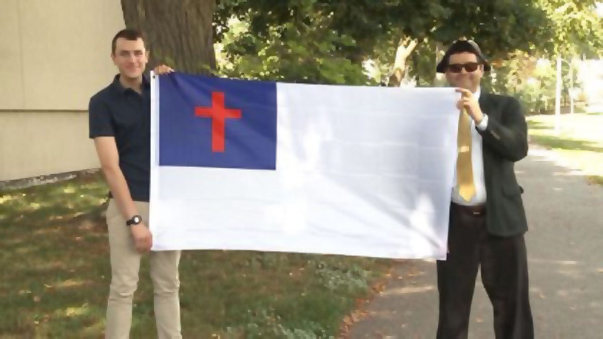 Nathaniel Shurtleff, counselor, and Tom Moor, instructor, for Camp Constitution hold the Christian flag, which was not allowed to fly by the city of Boston in 2017 and 2018. Now the group is suing the city for religious discrimination.