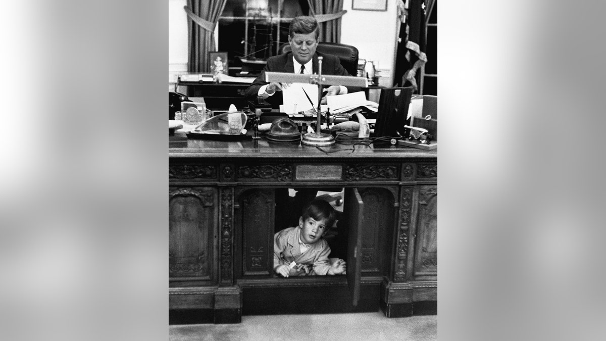 A young John F. Kennedy Jr. exploring his father's desk.