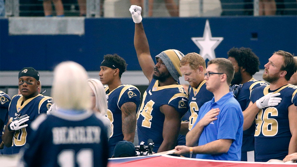 In this 2017 photo, then-Los Angeles Rams linebacker Robert Quinn (94) raising his fist during the anthem before a game against the Dallas Cowboys, in Arlington, Texas. (AP Photo/Ron Jenkins, File)