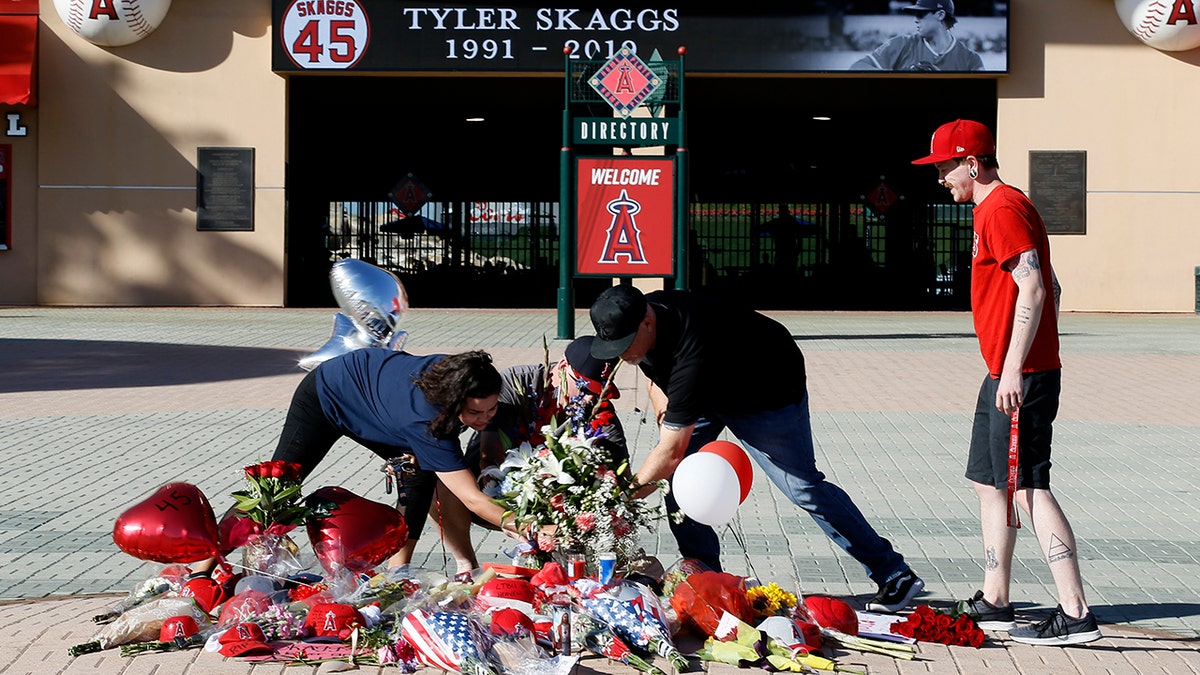 Los Angeles Angels fans prop up a memorial to give their condolences for pitcher Tyler Skaggs at Angel Stadium in Anaheim, Calif., Monday, July 1, 2019. Skaggs died at the age of 27, stunning Major League Baseball and leading to the postponement of the team's game against the Texas Rangers on Monday. (AP Photo/Alex Gallardo)
