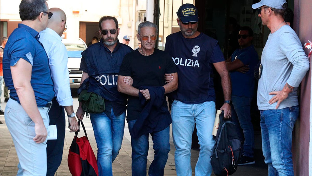Suspect Rosario Gambino, center, is taken into custody during an anti-mafia operation lead by the Italian Police and the FBI in Palermo, Southern Italy, Wednesday, July 17, 2019. Italian police and the FBI arrested 19 suspected Mafiosi in a joint operation Wednesday following an investigation which revealed alleged ties between Sicily's Cosa Nostra Mafia and New York's Gambino crime family.