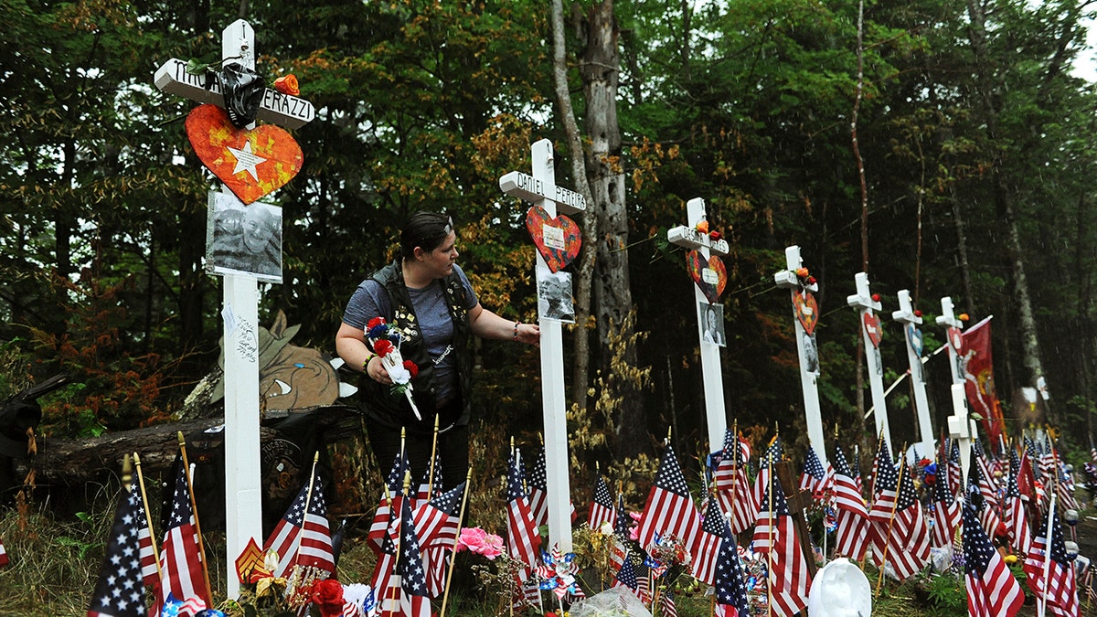 A woman views a memorial at the site where seven bikers riding with the Jarheads Motorcycle Club were killed in a collision last month Saturday. Thousands of motorcyclists converged at the crash site at the conclusion of the 90-mile Ride for the Fallen 7 to remember the riders who were killed. (Paul Hayes/Caledonian-Record via AP)