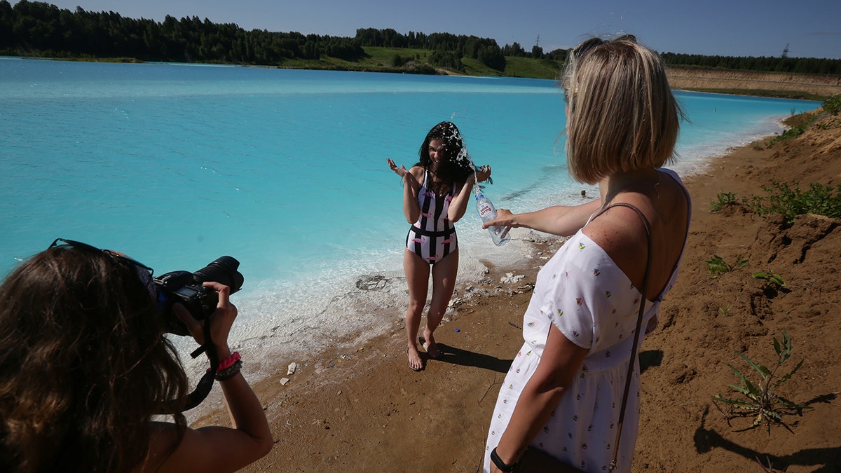 A young woman poses for pictures by a Novosibirsk energy plant's ash dump site - nicknamed the local "Maldives" - on July 11, 2019. - An industrial dump site in Siberia whose turquoise lake resembles a tropical paradise has become a magnet for Instagrammers who risk their health in the toxic water to wow online followers.