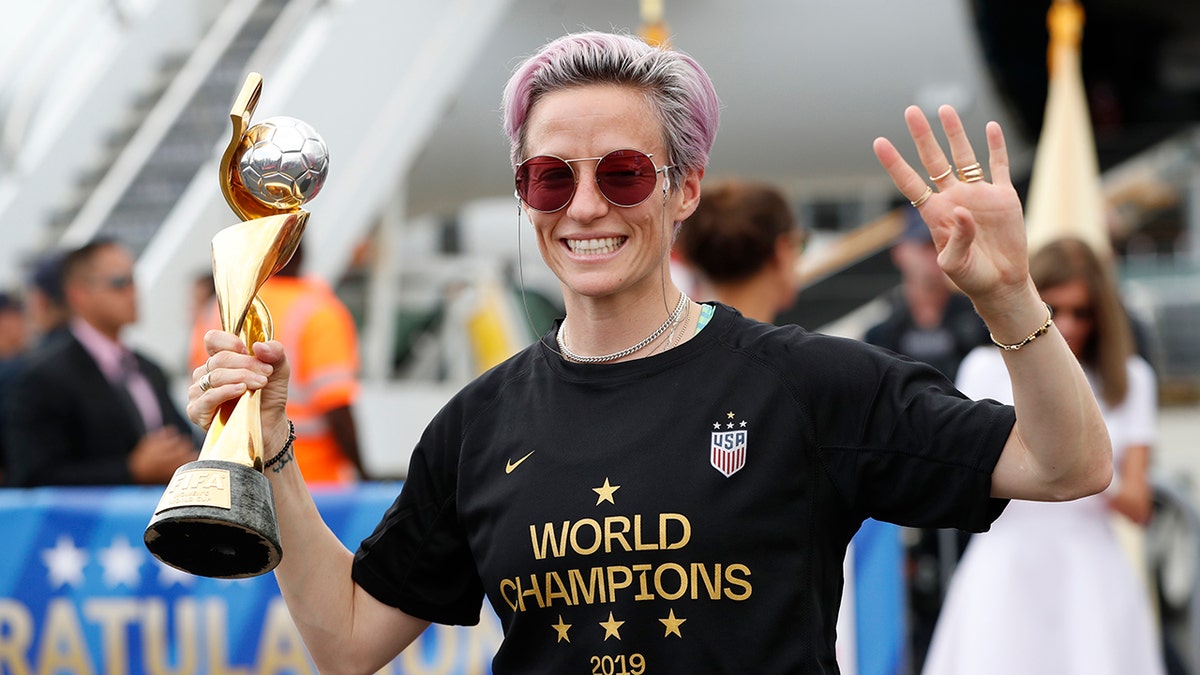 United States women's soccer team member Megan Rapinoe holds the Women's World Cup trophy as she celebrates in front of the media after arriving at Newark Liberty International Airport, Monday, July 8, 2019, in Newark, N.J. (AP Photo/Kathy Willens)