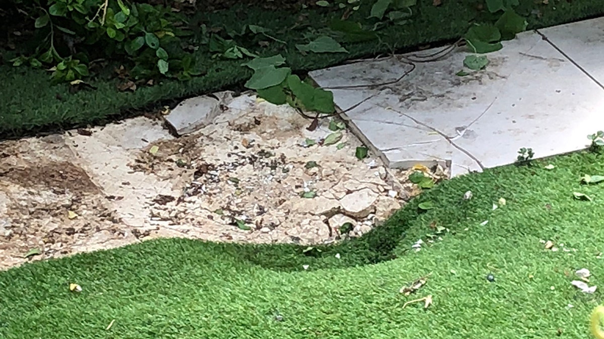 He landed partly on a small patio and partly on the grass, leaving cracked paving and a massive dent. (SWNS)