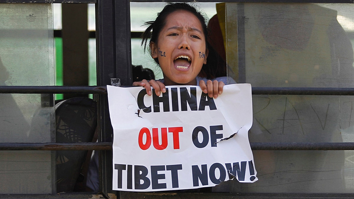 In this March 10, 2015 photo, a Tibetan exile shouts slogans against China after being detained inside a police bus during a protest in New Delhi, India. (AP Photo/Altaf Qadri, File)