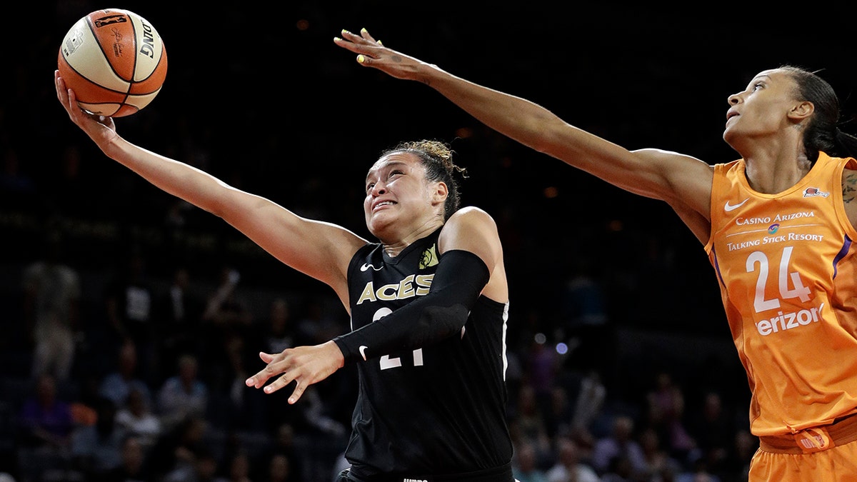 FILE - In this Aug. 1, 2018, file photo, Las Vegas Aces guard Kayla McBride shoots around Phoenix Mercury forward DeWanna Bonner during the second half of a WNBA basketball game in Las Vegas. McBride’s eyes light up when talking about the Las Vegas offense. With the addition of 6-foot-8 Liz Cambage in the offseason to join 6-5 A’ja Wilson in the Aces’ frontcourt, her life on the court as a shooter has gotten much easier. (AP Photo/John Locher, File)