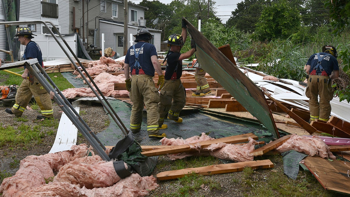 Yarmouth Fire crews look through the parts of the roof that blew off the Cape Sands Inn during a morning tornado that touched down on the structure, Tuesday, July 23, 2019, in West Yarmouth, Mass. (Steve Heaslip/The Cape Cod Times via AP)