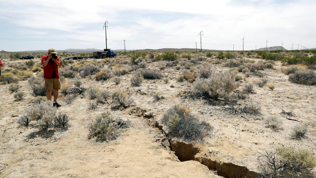 A visitor takes a photo of a crack on the ground following recent earthquakes outside of Ridgecrest, Calif. (AP Photo/Marcio Jose Sanchez)