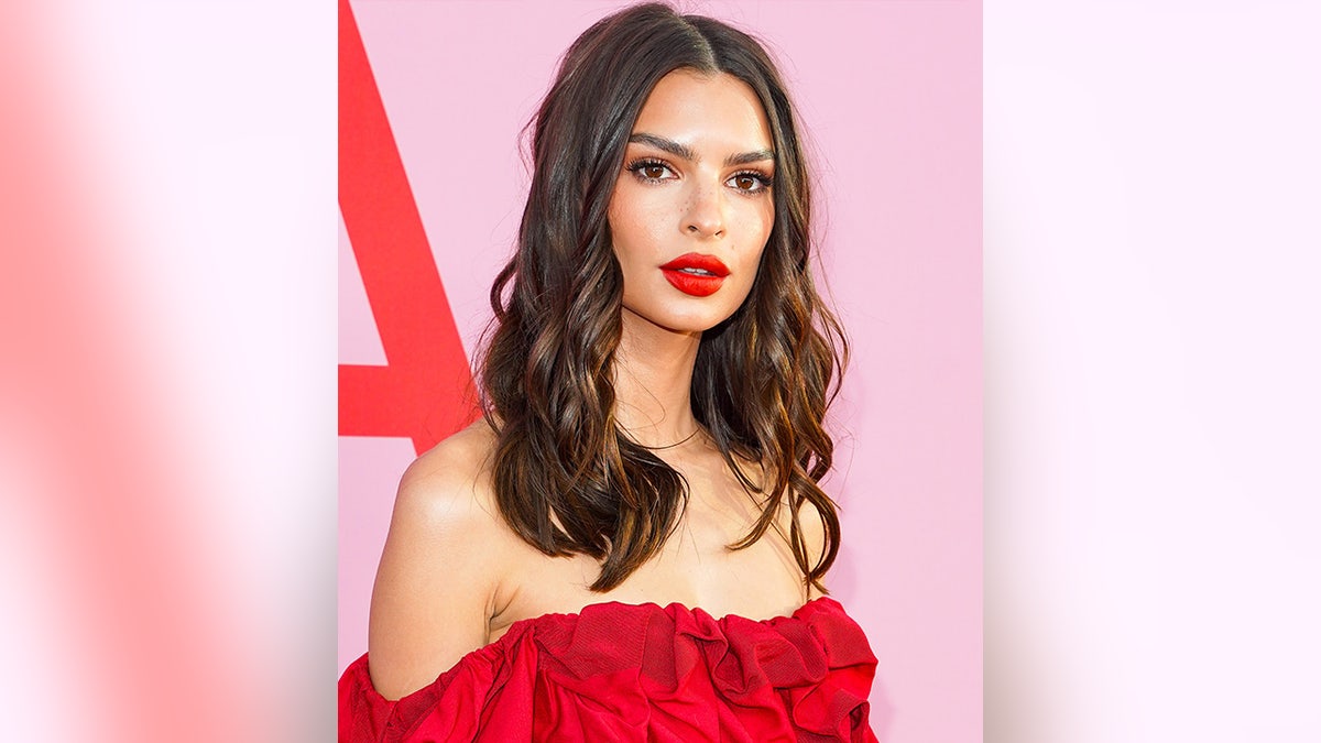 Emily Ratajkowski wearing a red off the shoulder look with red lipstick