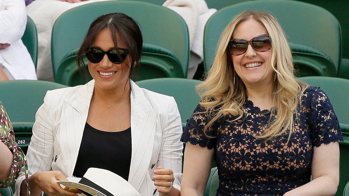 Meghan, Duchess of Sussex, left, smiles as she takes her seat on Court Number One to watch United States' Serena Williams play Slovenia's Kaja Juvan in a singles match during day four of the Wimbledon Tennis Championships. (AP Photo/Tim Ireland)