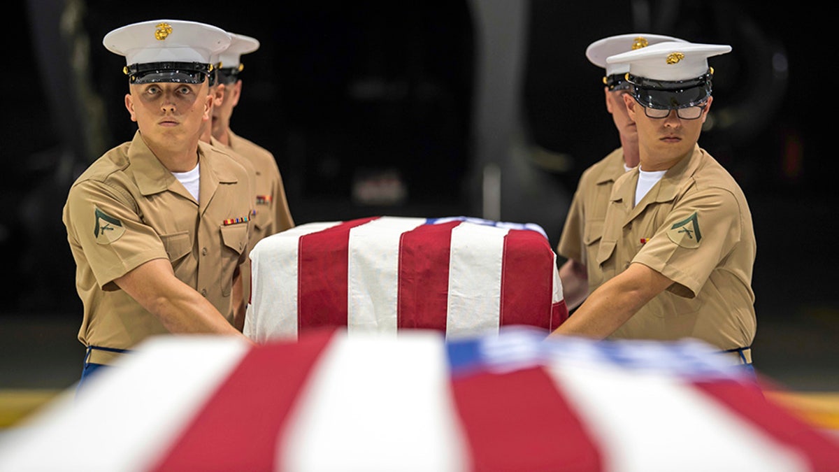 U.S. Marines carry transfer cases holding the remains of unidentified service members lost in the Battle of Tarawa during World War II, during what is known as an honorable carry conducted by the Defense POW/MIA Accounting Agency (DPAA), in a hangar at Joint Base Pearl Harbor-Hickam in Hawaii.