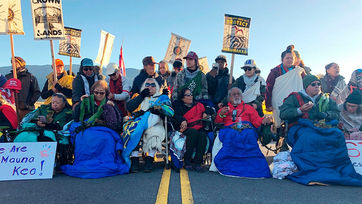 Demonstrators gather to block a road at the base of Hawaii's tallest mountain, on Monday. (AP)