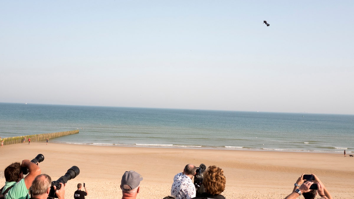 People watch as Franky Zapata, a 40-year-old inventor, takes to the air in Sangatte, Northern France, at the start of his attempt to cross the channel from France to England on July 25, 2019. 