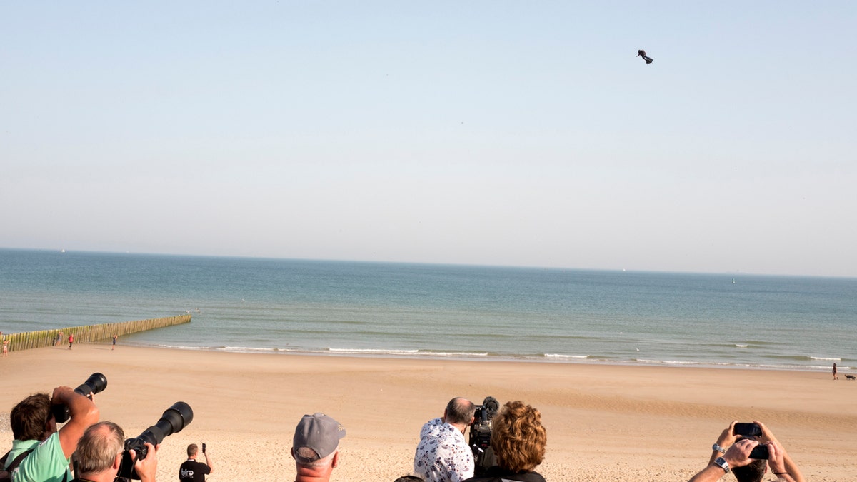 People watch as Franky Zapata, a 40-year-old inventor, takes to the air in Sangatte, Northern France, at the start of his attempt to cross the channel from France to England on July 25, 2019.