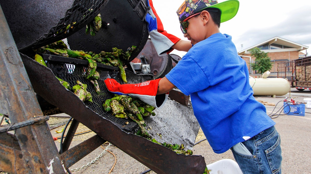 FILE - In this Aug. 9, 2017, file photo, Chris Duran Jr, 7 helps roast green chile with his family outside the Big Lots in Santa Fe, N.M. A hybrid version of a New Mexico chile plant has been selected to be grown in space as part of a NASA experiment, officials recently announced. (Gabriela Campos/Santa Fe New Mexican via AP, File)