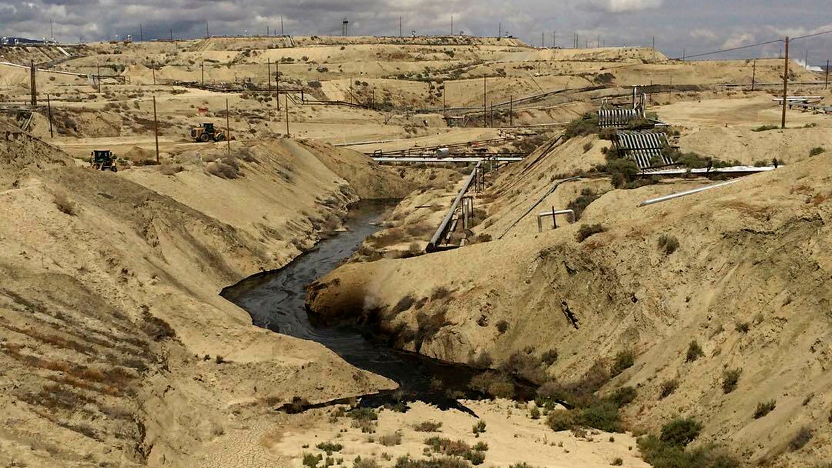 In this May 10, 2019 photo provided by the California Department of Fish and Wildlife's Office of Spill Prevention and Response, oil flows at a Chevron oil field in Kern County, Calif. Nearly 800,000 gallons of oil and water has seeped from the ground since May. (California Department of Fish and Wildlife's Office of Spill Prevention and Response via AP)