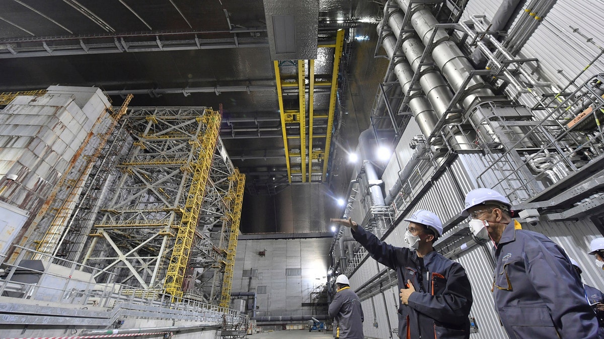 In this June 1, 2019, file photo, French Foreign Minister Jean-Yves Le Drian, right, listens to an employee inside the New Safe Confinement (NSC) movable enclosure at the nuclear power plant in Chernobyl, Ukraine. A new structure built to confine the Chernobyl reactor at the center of the world's worst nuclear disaster was previewed for the media Tuesday, July 2. (Sergei Supinsky/Pool Photo via AP, File)