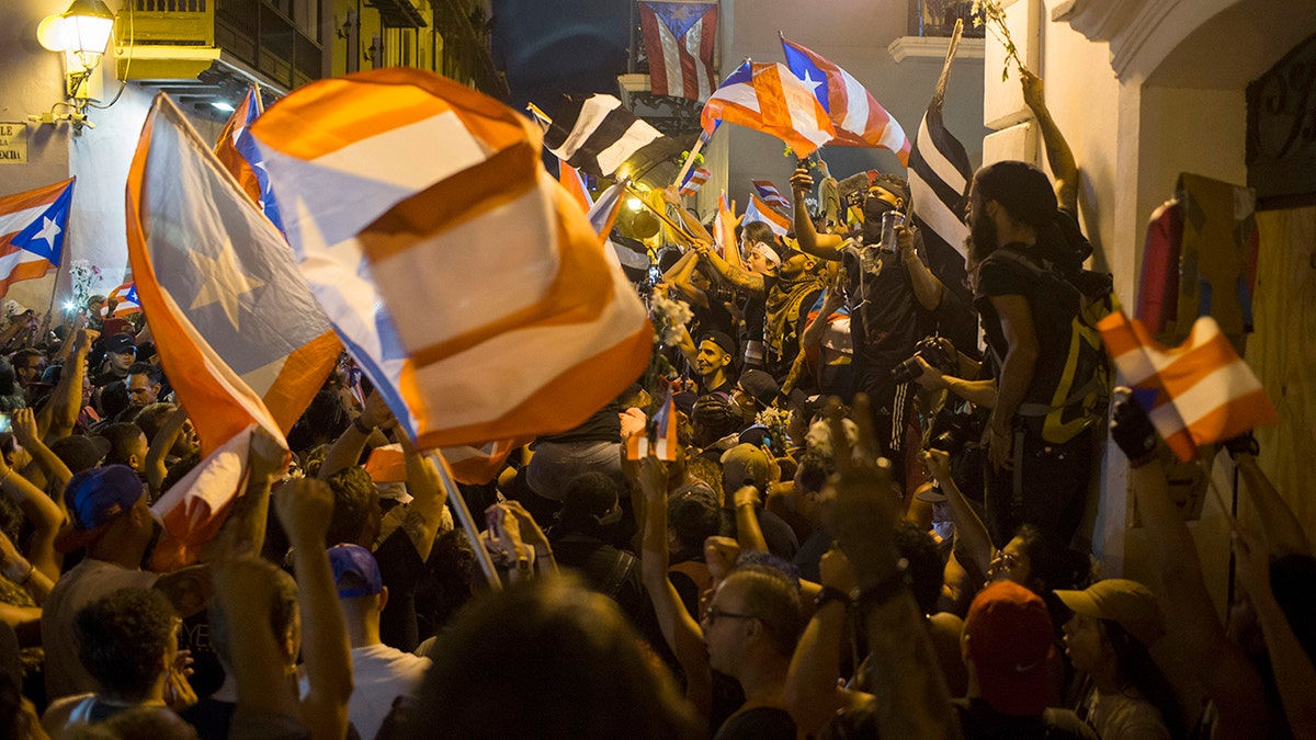 People celebrate outside the governor's mansion La Fortaleza, after Gov. Ricardo Rossello announced that he is resigning. (AP Photo/Dennis M. Rivera Pichardo)