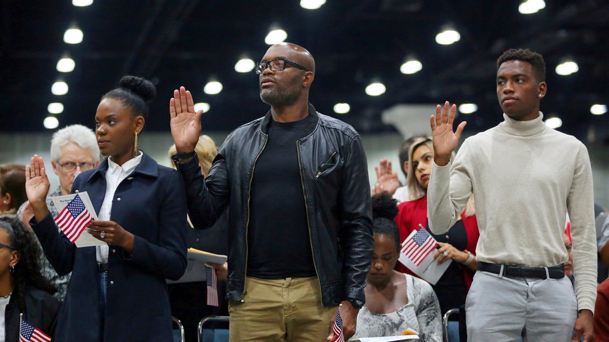 Mixed martial arts great Anderson "Spider" Silva of Brazil, center, his daughter Kaory, 23, left, and son Kalyl, 20, are is sworn in as a U.S. citizen along with thousands of others in a mass naturalization ceremony Tuesday, July 23, 2019 at the Los Angeles Convention Center. (AP Photo/Reed Saxon)