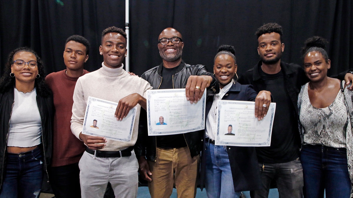 Mixed martial arts great Anderson "Spider" Silva of Brazil, center, his daughter Kaory, 23, right, and son Kalyl, 20, left, hold their citizenship documents after they are sworn in as U.S. citizens in a mass naturalization ceremony Tuesday, July 23, 2019 at the Los Angeles Convention Center. Joining them are family members who are not yet citizens, from left, daughter Kauana, 18; Joao, 14; and son Gabriel, 22, and Anderson Silva's wife Dayane. (AP Photo/Reed Saxon)