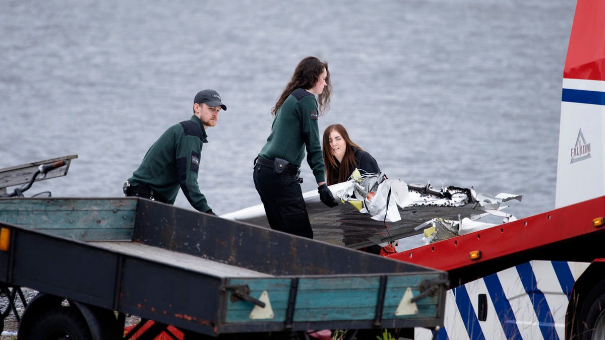 Emergency personnel move a part of a wing and other plane wreckage retrieved from the crash site at Ume river outside Umea, Sweden, on Monday July 15, 2019.