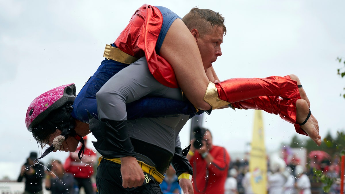 People take part in the wife carrying race, a 278-yard obstacle course, during the 24th world championships in Sonkajarvi, Finland, Saturday, July 6, 2019. (AP Photo/David Keyton)