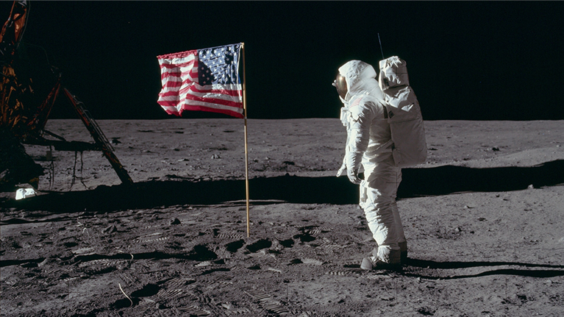 Astronaut Edwin E. Aldrin Jr., the lunar module pilot of the first lunar landing mission, poses for a photograph beside the deployed United States flag during an Apollo 11 extravehicular activity on the lunar surface.