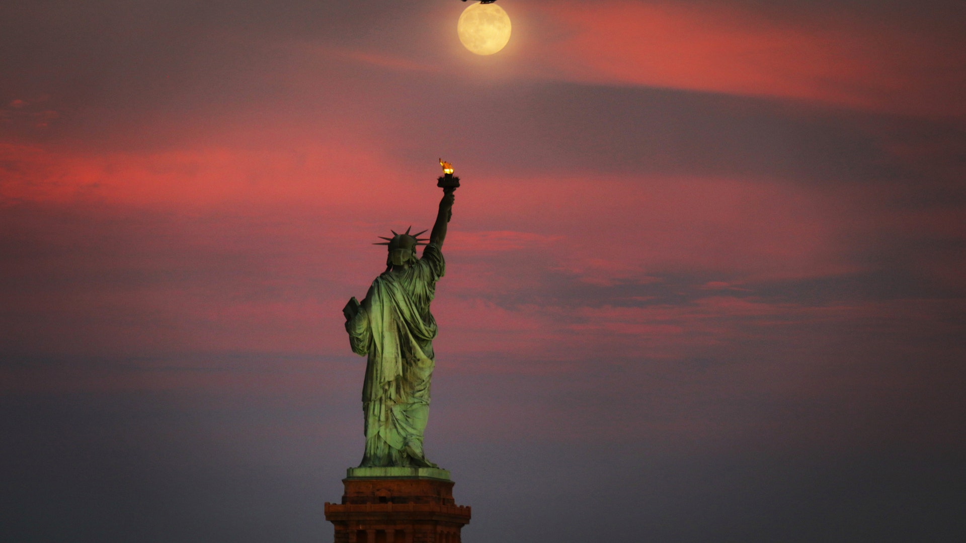 The moon rises above the Statue of Liberty in New York City, July 15, 2019.