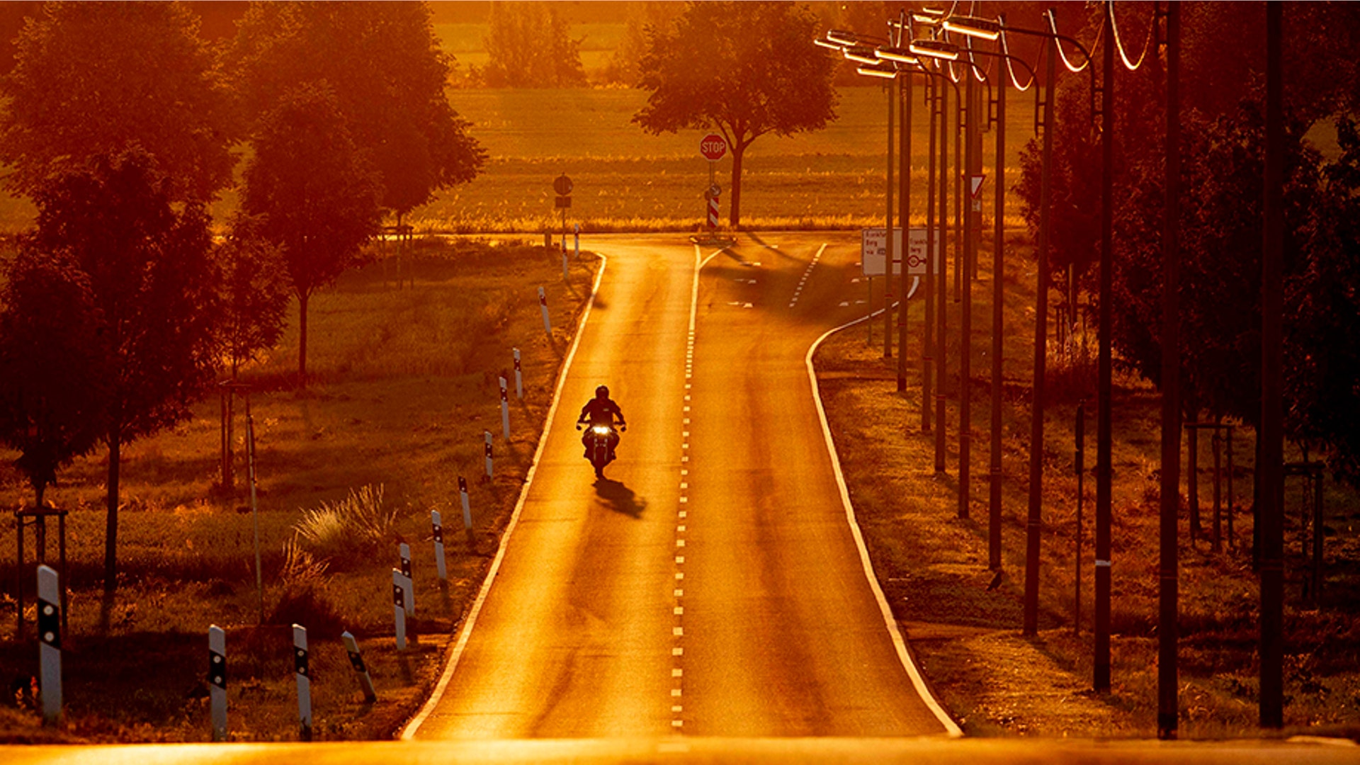 A man rides his motorcycle as the sun rises in the outskirts of Frankfurt, Germany, July 4, 2019. 