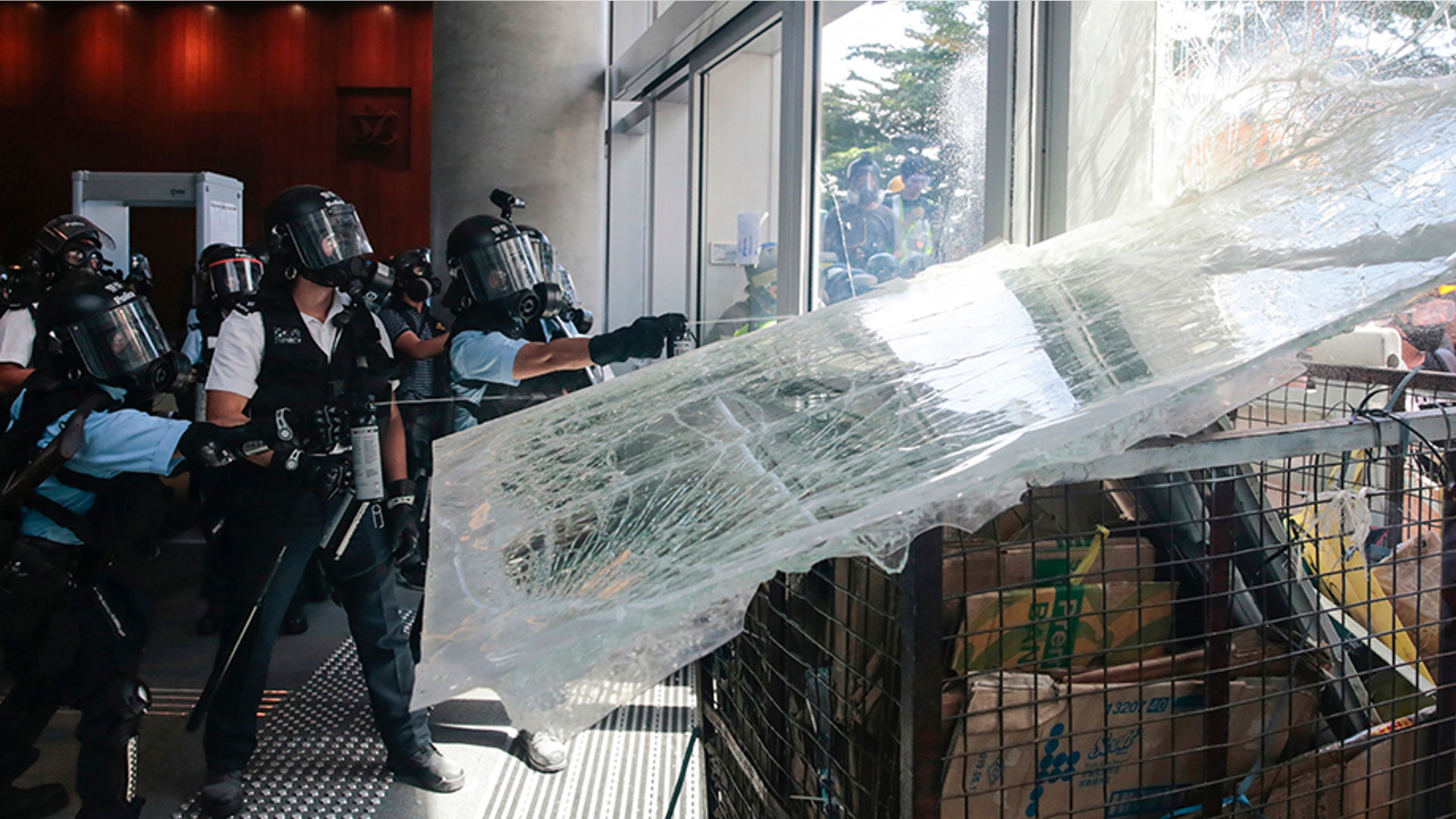 Police officers hit protesters with pepper spray as they use a cart to ram into the glass wall of the Legislative Council in Hong Kong, July 1, 2019. 